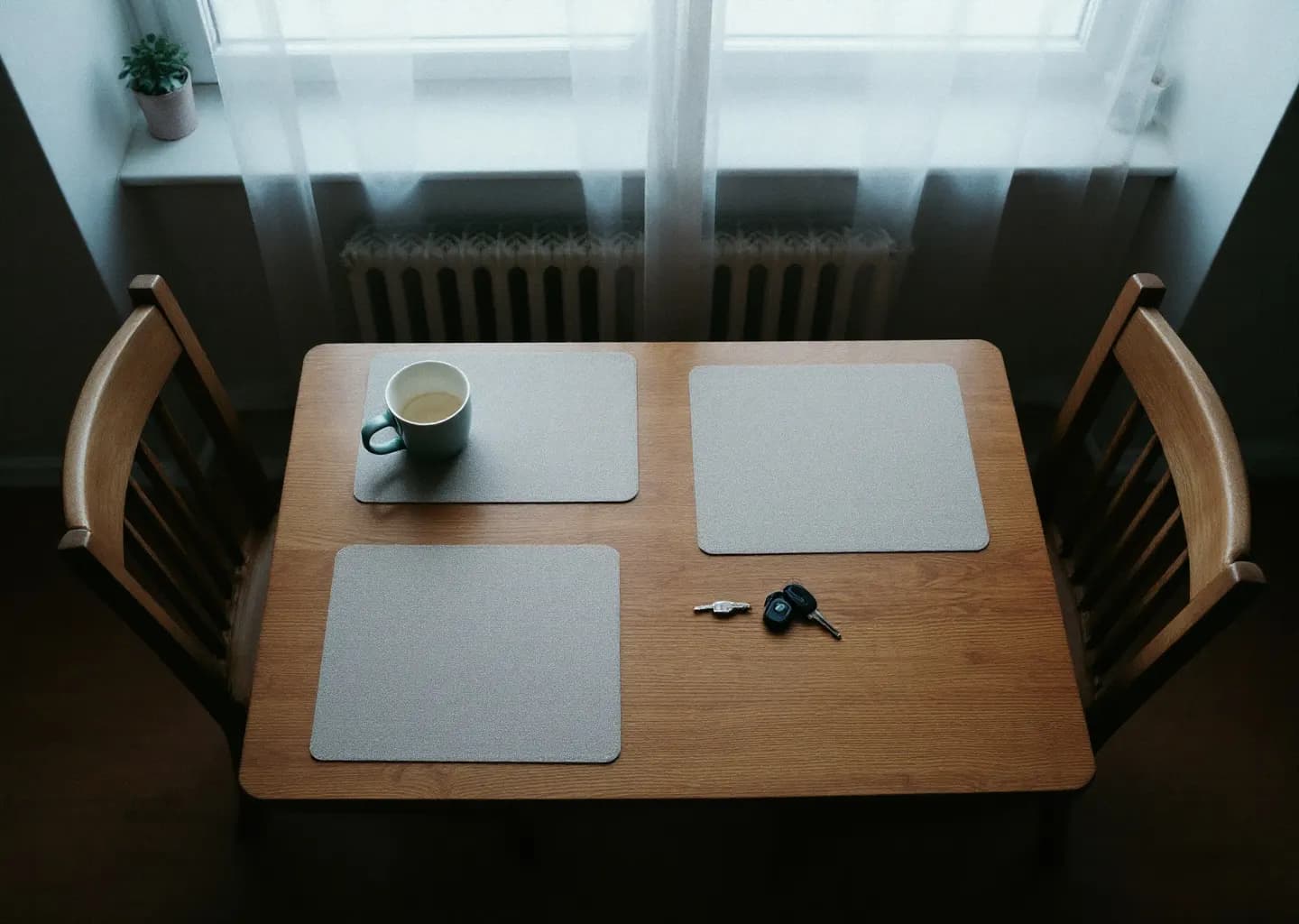 Table de cuisine avec deux chaises, une seule tasse utilisée et un trousseau de clés